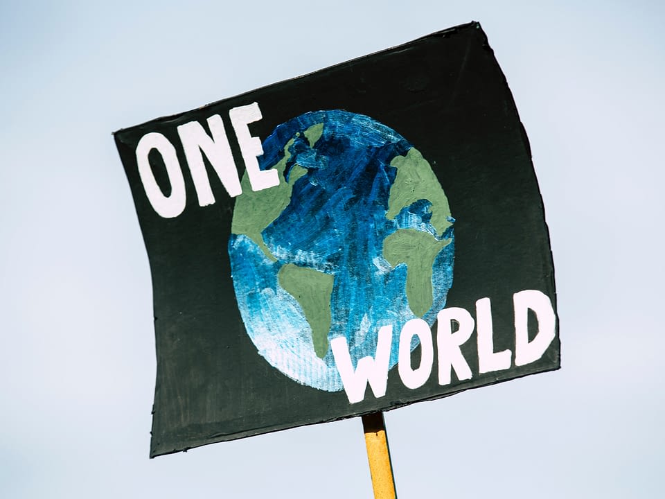 poster held in the sky with an image of the world and the words ONE WORLD written