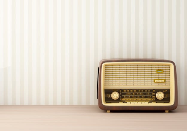 Image of an dark brown old radio in front of a striped wall 